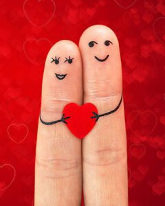 Happy couple in love with painted smiley holding red heart